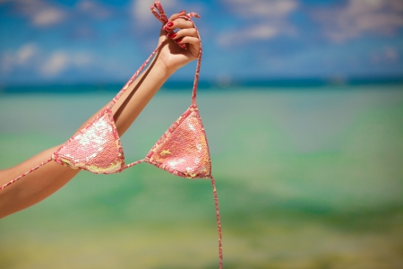 Woman's hand holding pink bra background the seaの写真素材