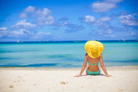 Beautiful back side of model in bikini and hat sitting down.の写真素材