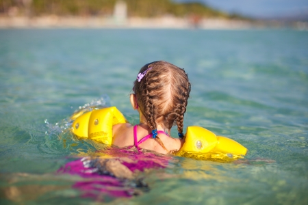 Adorable little girl swimming in the sea on tropical beach vacationの写真素材