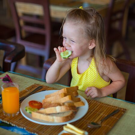 Cute little girl having breakfast at resort restaurantの写真素材