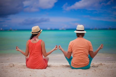 Young couple enjoying each other and yoga on a beachの写真素材