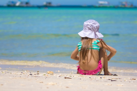 Adorable little girl in swimsuit playing at tropical beachの写真素材