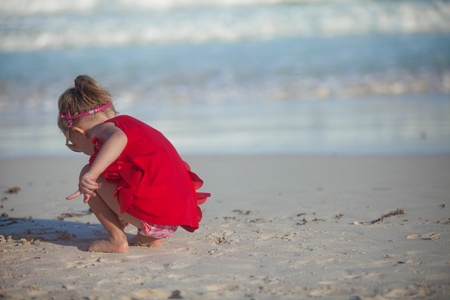 Adorable little girl in red dress playing at tropical beachの写真素材