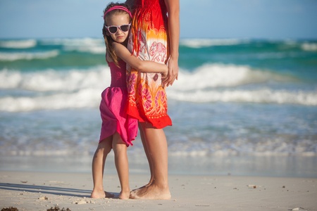 Close-up little girl is holding her young mother at the beachの写真素材