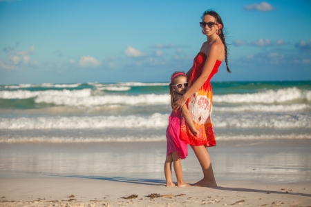 Nice young mother and her cute daughter walking on tropical beachの写真素材