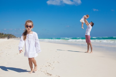 Young dad and his cute daughters having fun on white beachの写真素材