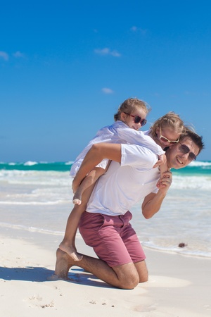 Young dad and his cute daughters having fun on white beachの写真素材