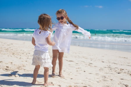 Two little sisters in white clothes have fun at tropical beach in Mexicoの写真素材