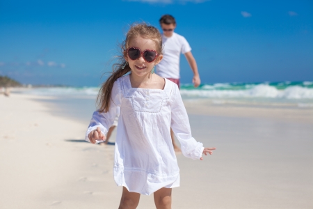 Portrait of adorable girl and his father with little sister in the background at tropical beachの写真素材