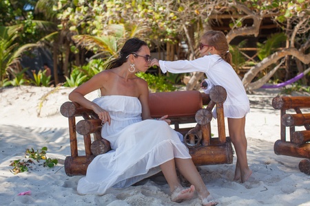 Young mother and her little daughters smelling flowers on tropical beachの写真素材