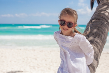 Closeup of smiling girl sitting on palm tree at the perfect caribbean beachの写真素材