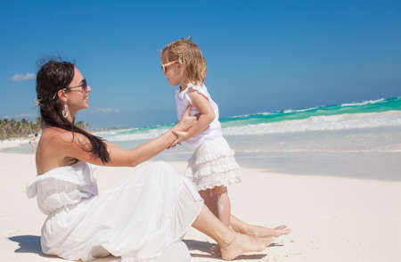 Young beautiful mother and her adorable little daughter at tropical beachの写真素材