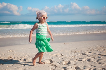 Little girl walking on white sandy beach in Mexicoの写真素材