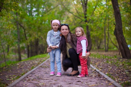 Young mother with her little daughters looking to camera oudoorの写真素材