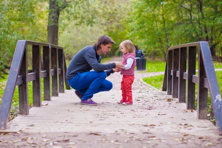 Young father walking with his little daughter in autumn parkの写真素材