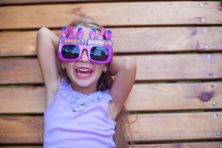 Adorable little girl in Happy Birthday glasses have fun outdoorの写真素材