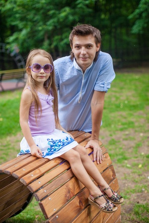 Portrait of father with his daughter on the wooden plank bed in the parkの写真素材