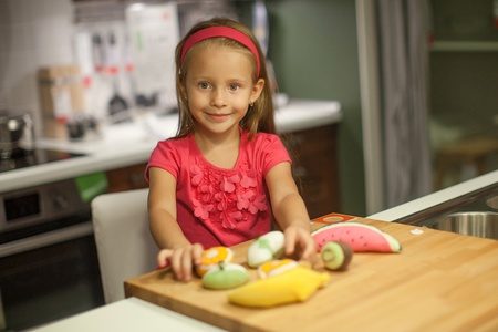 Little cute girl playing in the kitchen with fruits and vegetablesの写真素材