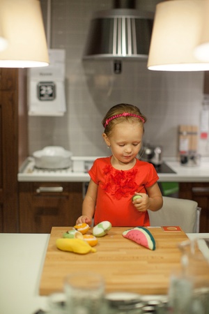 Little cute girl playing in the kitchen with fruits and vegetablesの写真素材