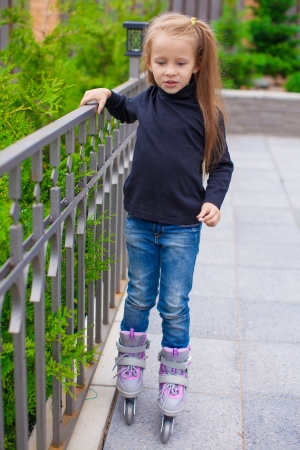 Little cute girl on roller skates in front of her houseの写真素材