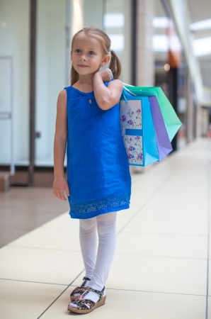 Little fashion girl with packages in large shopping centerの写真素材