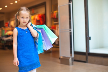 Portrait of little fashion girl holding shopping bags at the mallの写真素材