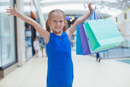 Portrait of little happy girl holding shopping bags at the mallの写真素材