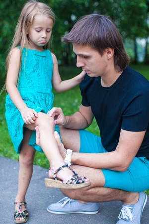 Young father pities his little daughter, who hurt her legの写真素材