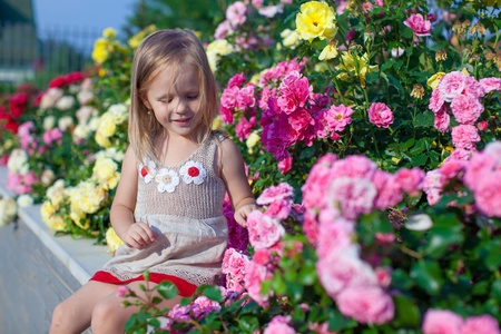 Portrait of cute little girl near the flowers in the yard of her houseの写真素材