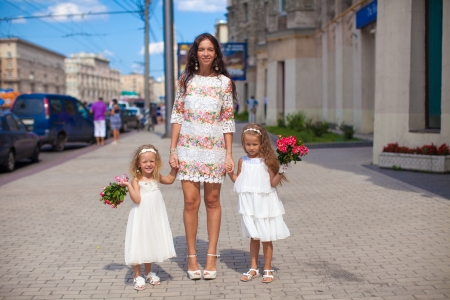 Two charming sisters with beautiful bouquets and their mother in the streetの写真素材