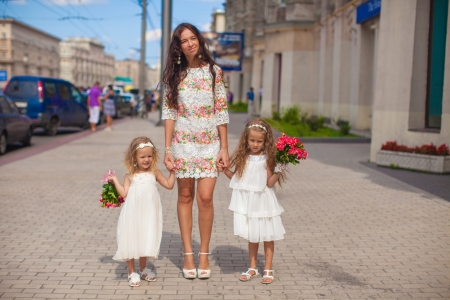 Two charming sisters with beautiful bouquets and their mother in the streetの写真素材