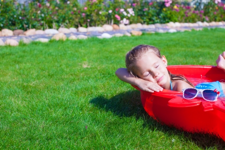 Portrait of relaxing charming little girl enjoying her vacation in small poolの写真素材