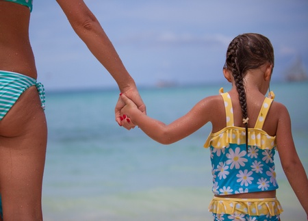Close-up hands of her mother and daughter walking on the beachの写真素材