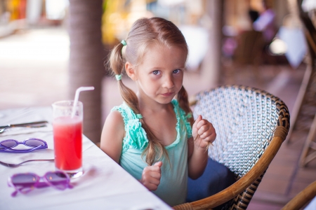 Little girl sitting in chair at restaurant waiting for her foodの写真素材