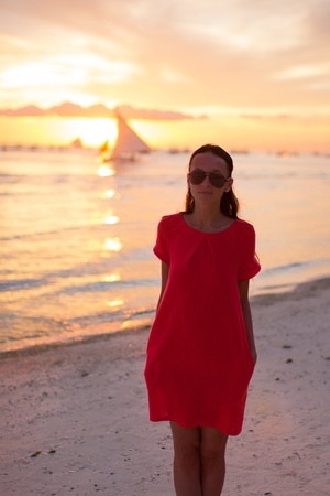 Silhouette of young beautiful woman at tropical beach in sunsetの写真素材