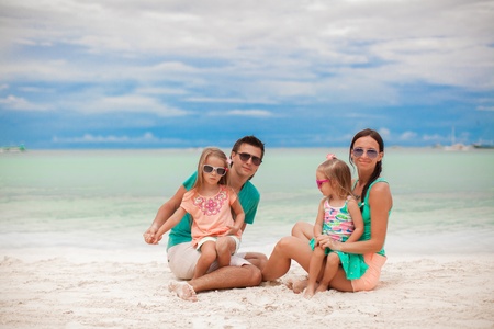 Young beautiful family with two daughters having fun at beachの写真素材