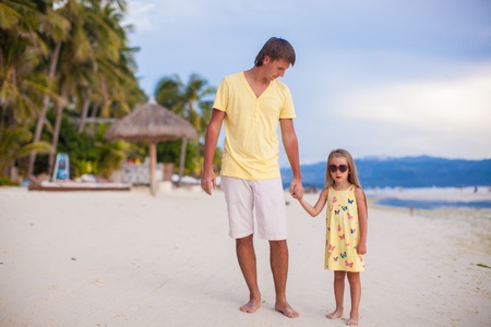 Happy father with his adorable daughter walking on tropical beach vacationの写真素材