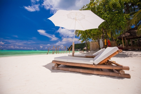 Paradise view of nice tropical empty sandy plage with umbrella and beach chairの写真素材