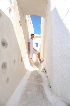 Young woman walking in the narrow streets of the village of Emporio on the island of Santorini in Greeceの写真素材