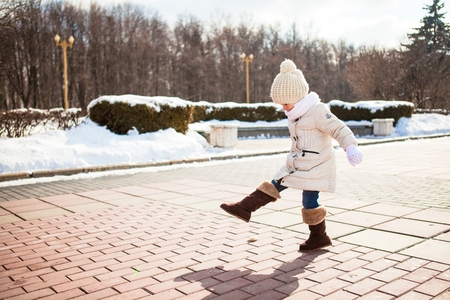 Little cute girl walks in the winter on a sunny day outdoorsの写真素材