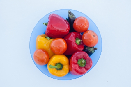 Deep plate with delicious vegetables  peppers, eggplant and tomatoes on white snowの写真素材