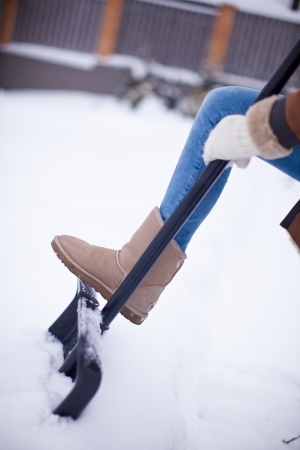 Women s feet at winter boots on snow shovel