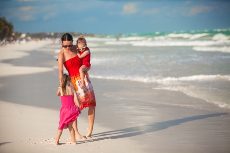 Young mother and two her fashion daughters walking at exotic beach on sunny dayの写真素材