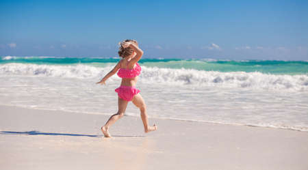 Little cute girl running on the white sandy beach in Mexicoの写真素材