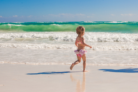 Little cute girl running on the white sandy beach in Mexicoの写真素材