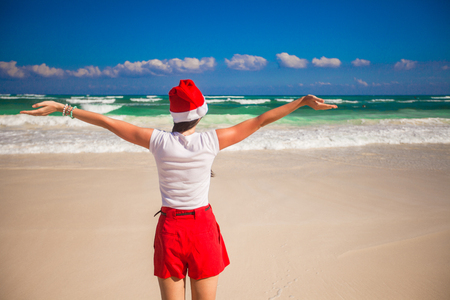 Young woman in Santa Hat walking spread her hands on white sandy beachの写真素材