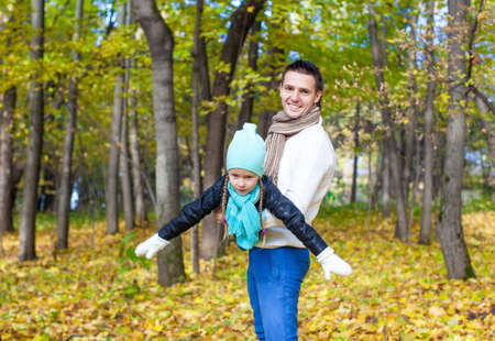 Happy dad and his little daughter having fun in the park on a sunny autumn dayの写真素材