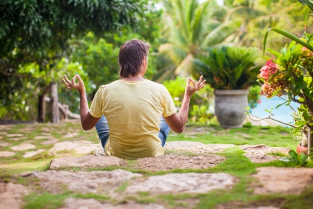 Young man sitting in the lotus position near the swimming poolの写真素材