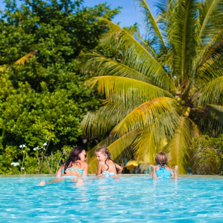 Two daughters and young mother relaxing in the luxury quiet swimming pooの写真素材
