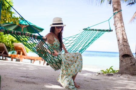 Happy young woman relaxing in the hammock on tropical beachの写真素材